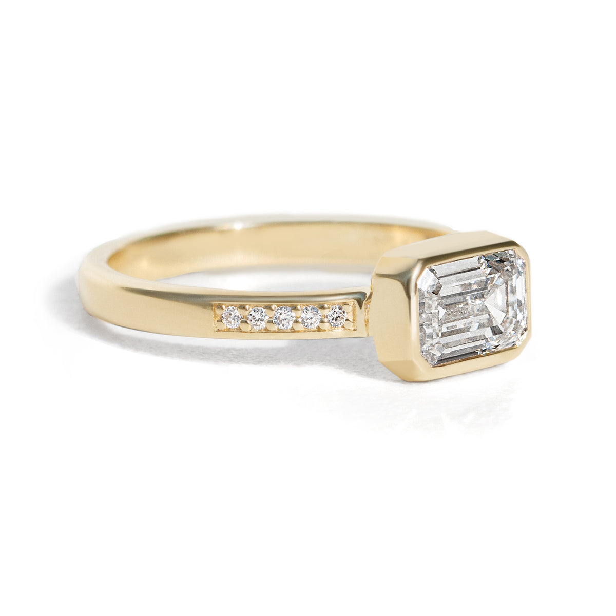 The Zoey Ring features a 1-carat emerald-cut diamond or moissanite in an east-west setting. The smooth bezel setting ensures everyday wear, while delicate accent diamonds add sparkle from every angle