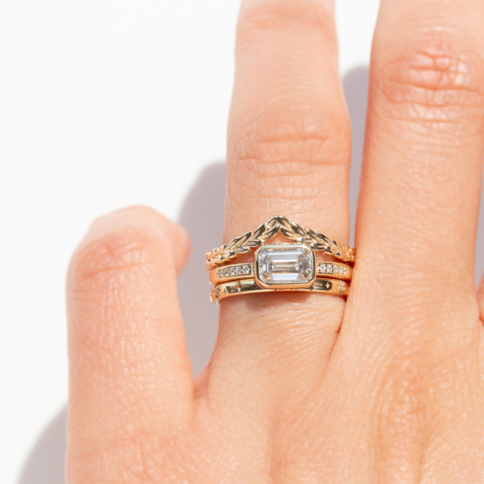 The Zoey Ring features a 1-carat emerald-cut diamond or moissanite in an east-west setting. The smooth bezel setting ensures everyday wear, while delicate accent diamonds add sparkle from every angle