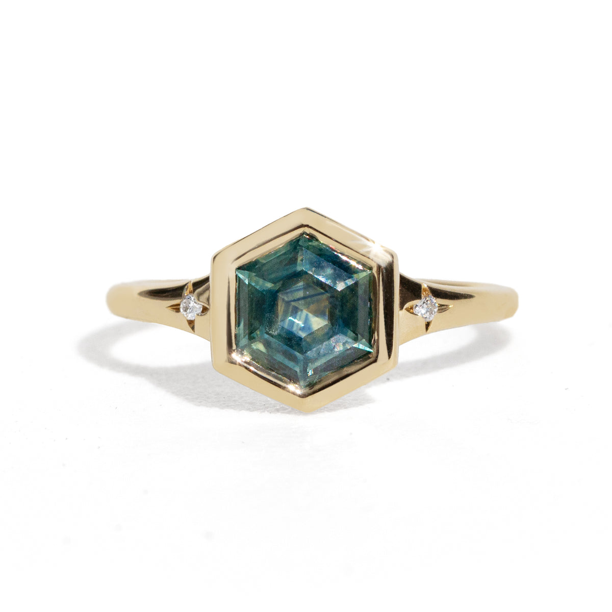 Gold ring with a green hexagon sapphire with two side diamonds on a white background
