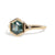 Gold ring with a green hexagon sapphire with two side diamonds on a white background