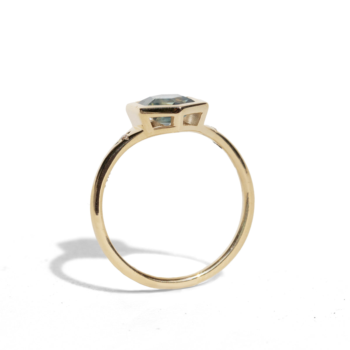Gold ring with a green hexagon sapphire with two side diamonds on a white background