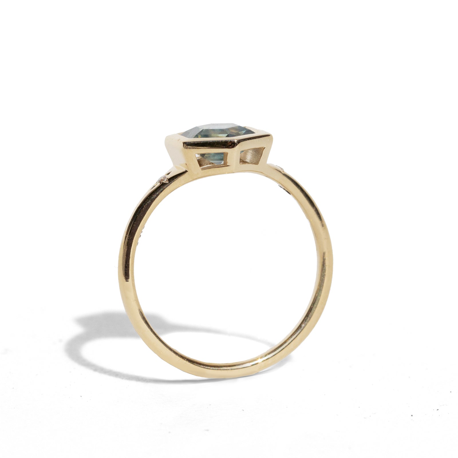 Gold ring with a green hexagon sapphire with two side diamonds on a white background