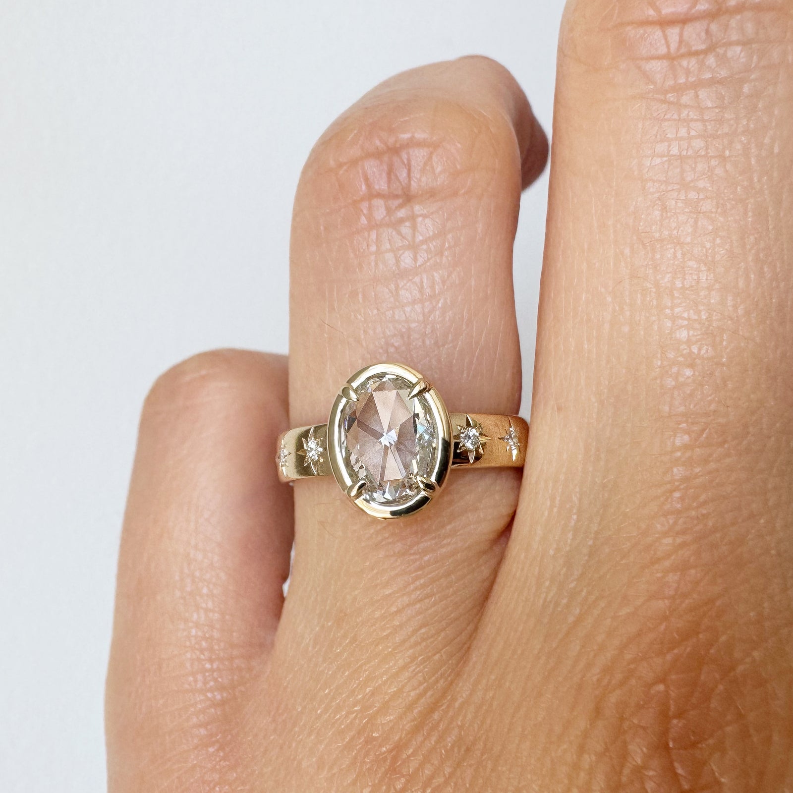 Gold ring with a diamond on a finger against a white background