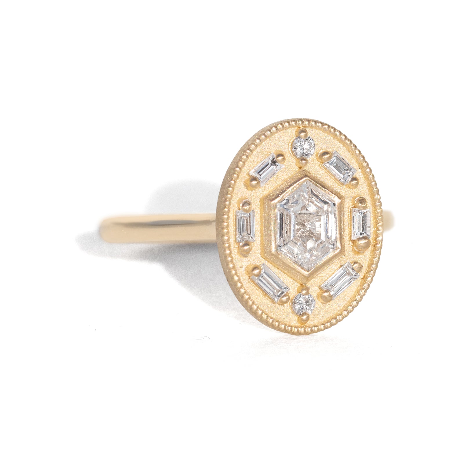 Gold ring with diamond accents around a hexagon diamond in the center on a white background