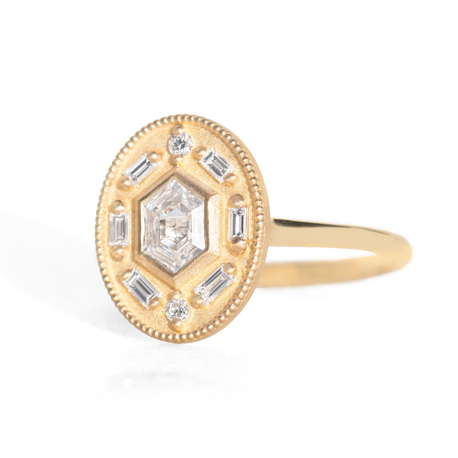 Gold ring with diamond accents around a hexagon diamond in the center on a white background