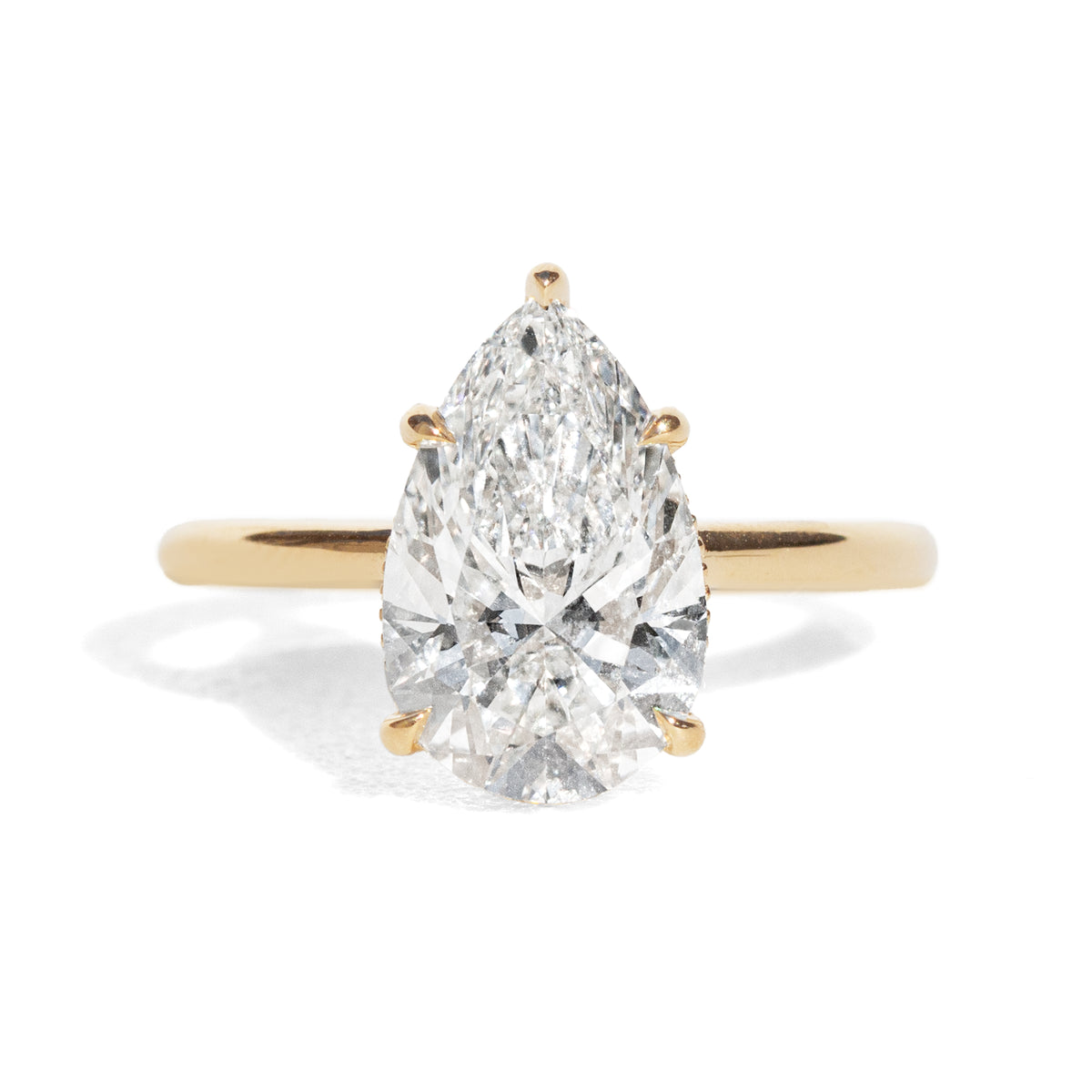 Gold ring with a pear-shaped diamond on a white background