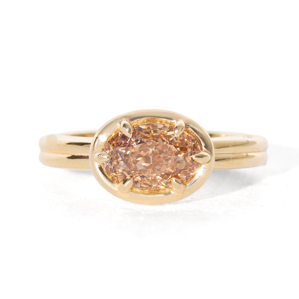 A yellow gold oval ring featuring a light brown-colored oval diamond in a six-prong setting, shown on a clean white background.
