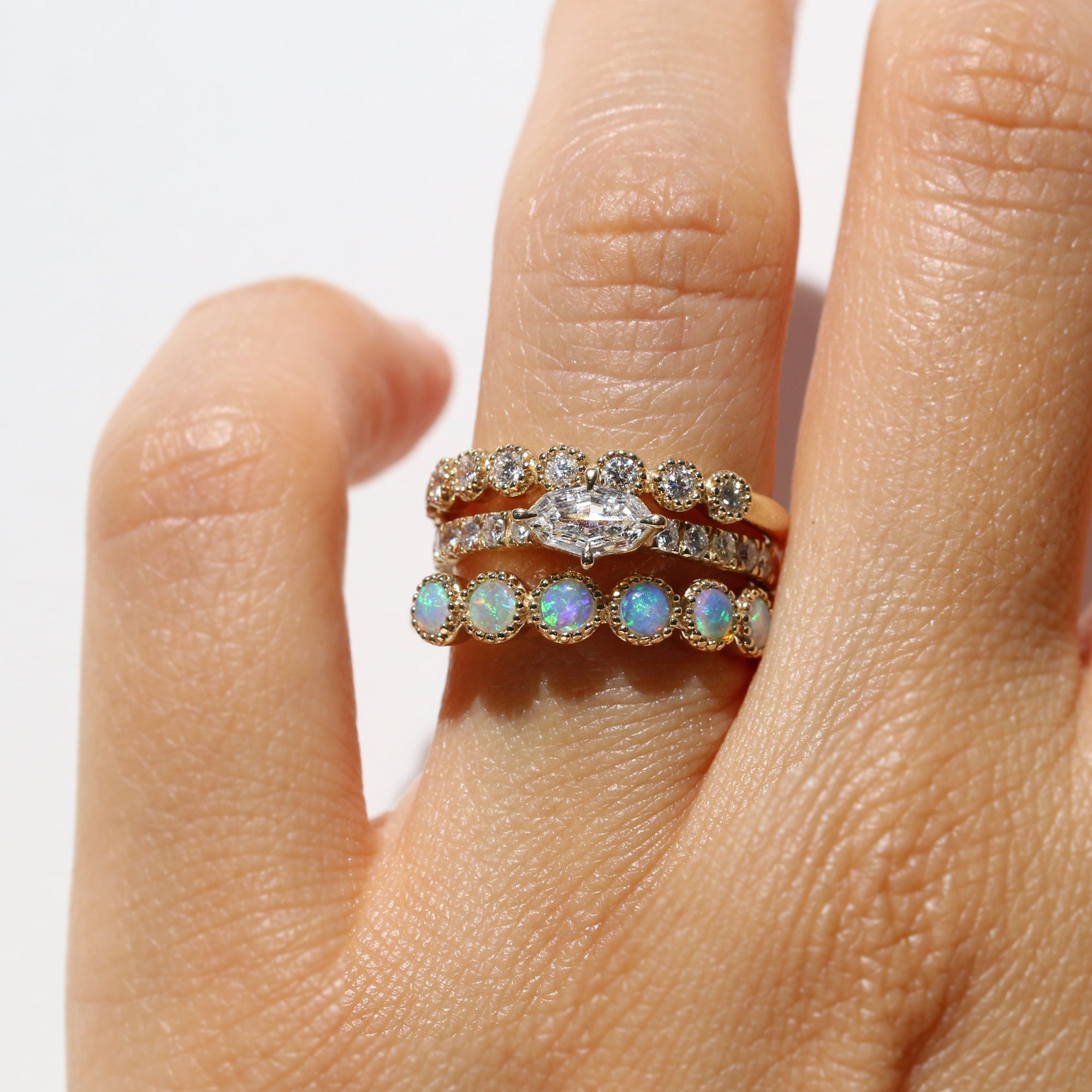 Stack of three rings with gemstones on a finger against a white background