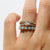Stack of three rings with gemstones on a finger against a white background