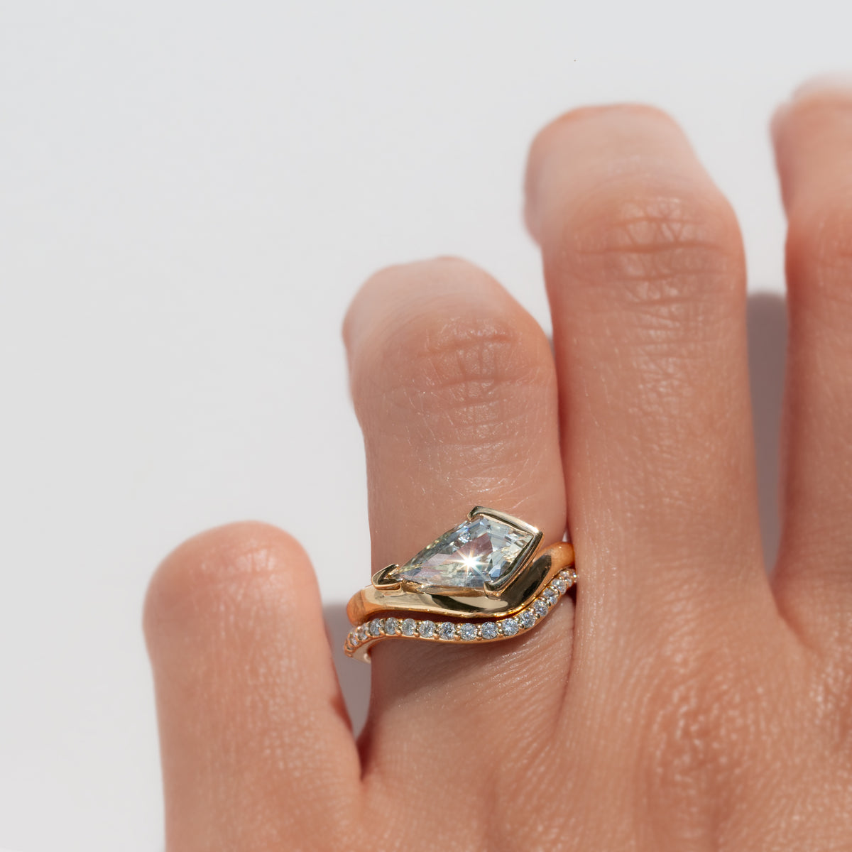 Gold ring with a large sapphire on a finger against a light background