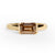 Gold ring with an emerald cut champagne diamond  on a white background