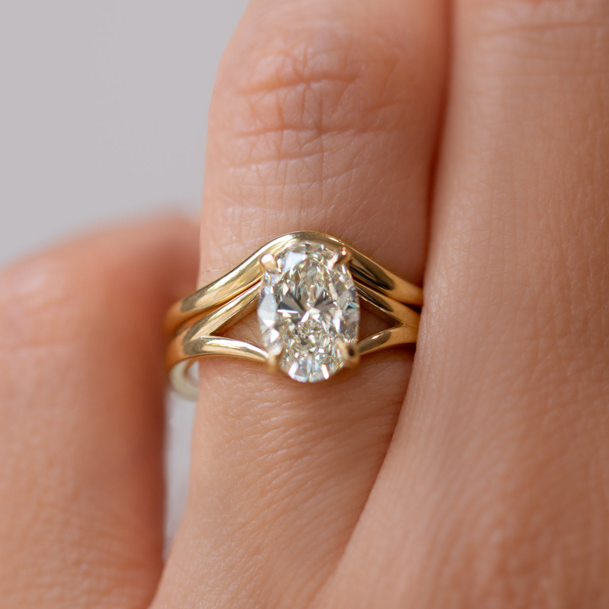Gold ring with a diamond on a finger against a neutral background