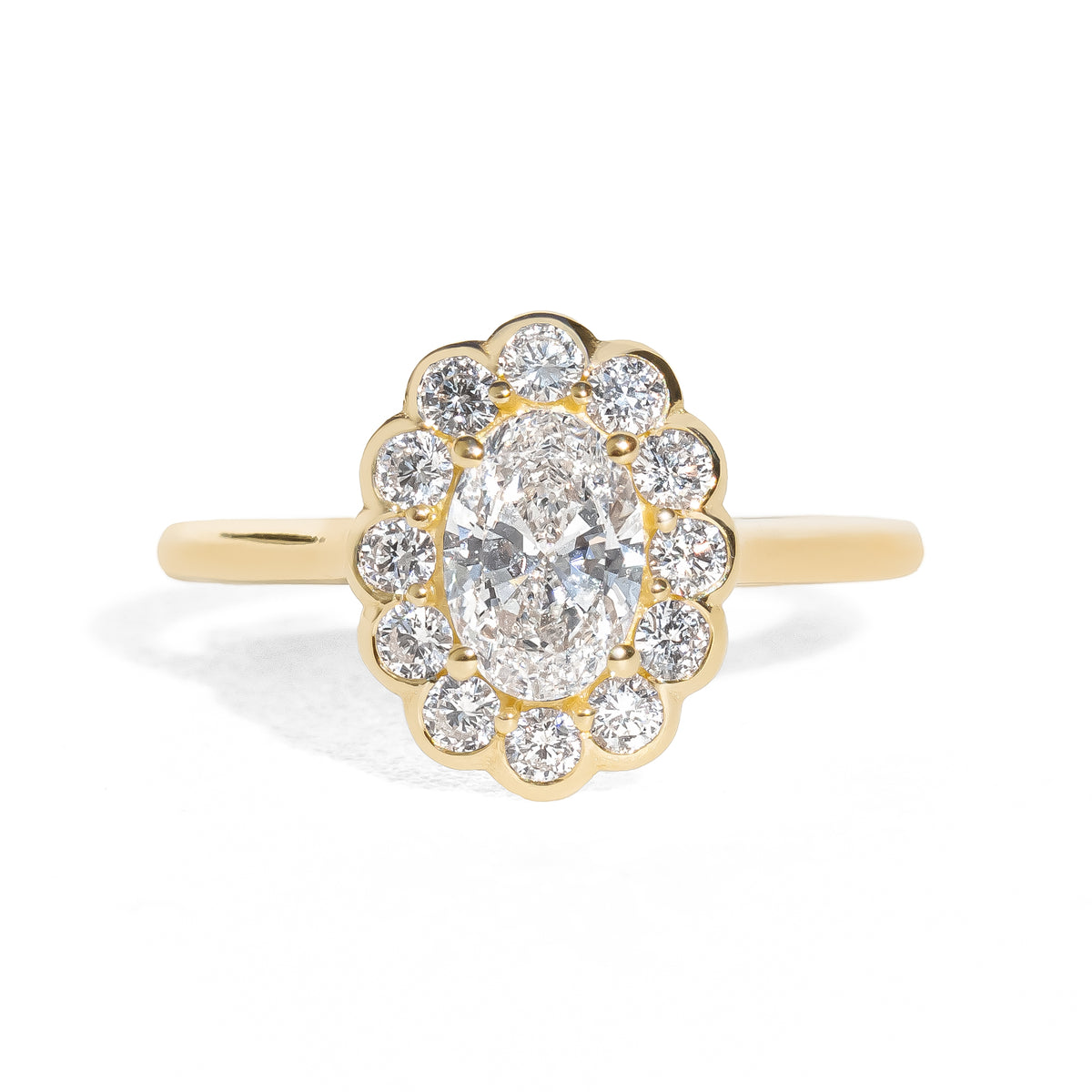 Gold ring with an oval diamond framed by small round halo diamonds on a white background