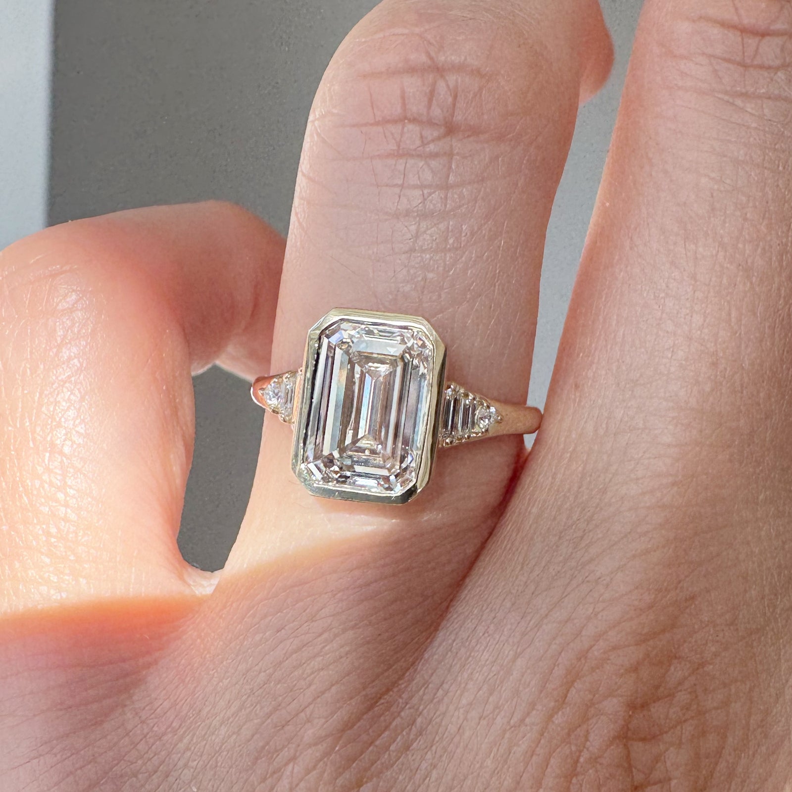 Diamond ring on a finger with a neutral background