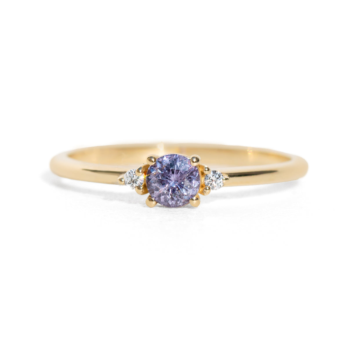 Gold ring with a purple sapphire on a white background