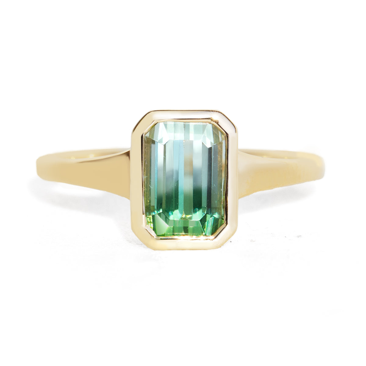 A yellow gold ring featuring a rectangular emerald-cut green gemstone with a gradient of light and dark green, set against a clean white background.