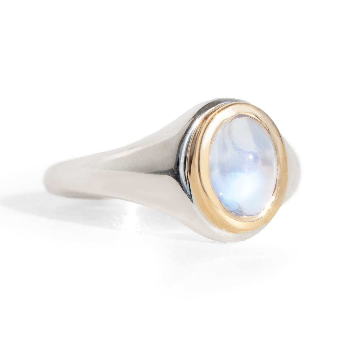 Ring with a blue moonstone and gold bezel setting on a silver band against a white background