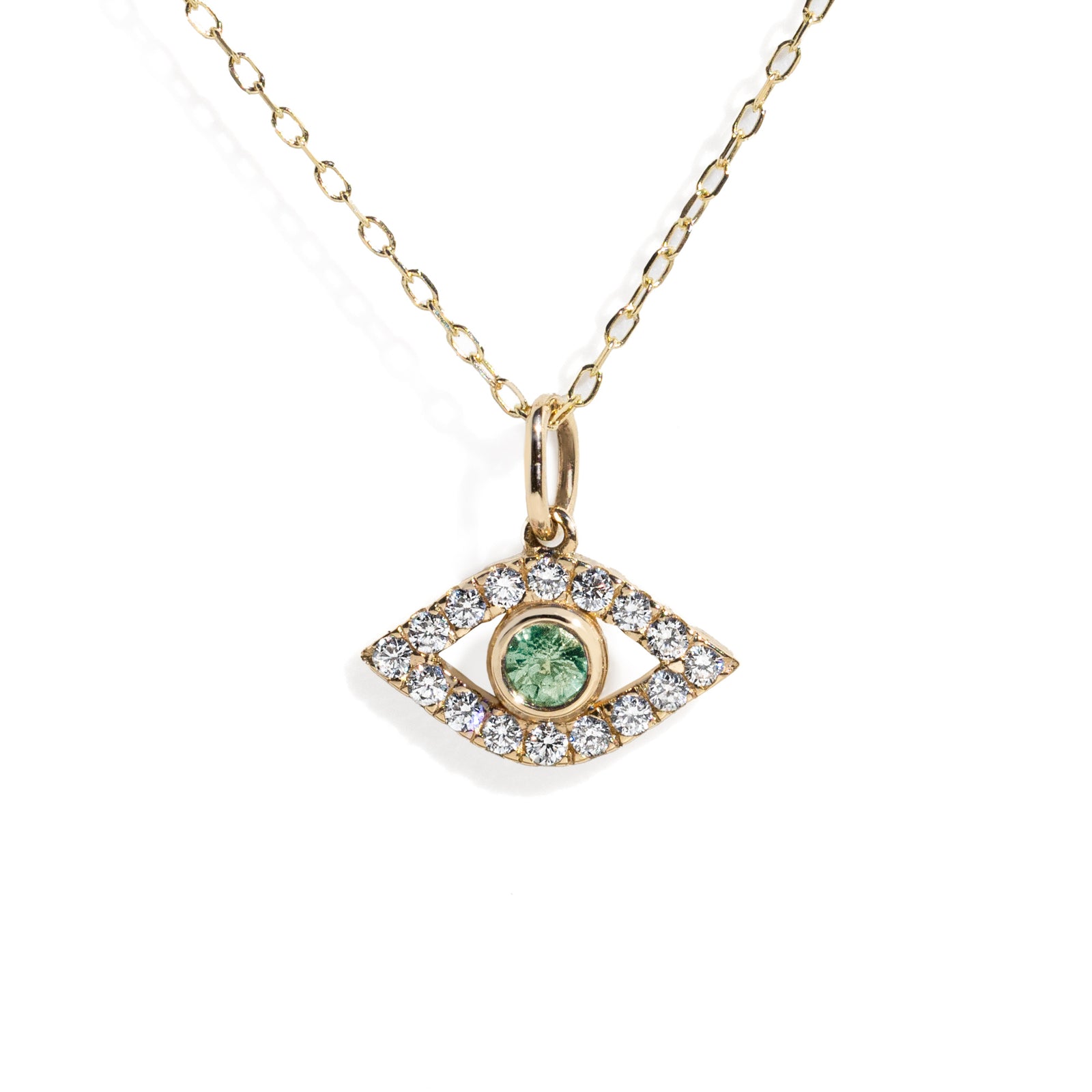 Gold eye charm with a green sapphire in the center surrounded by white diamond frame on a gold chain against white background. 