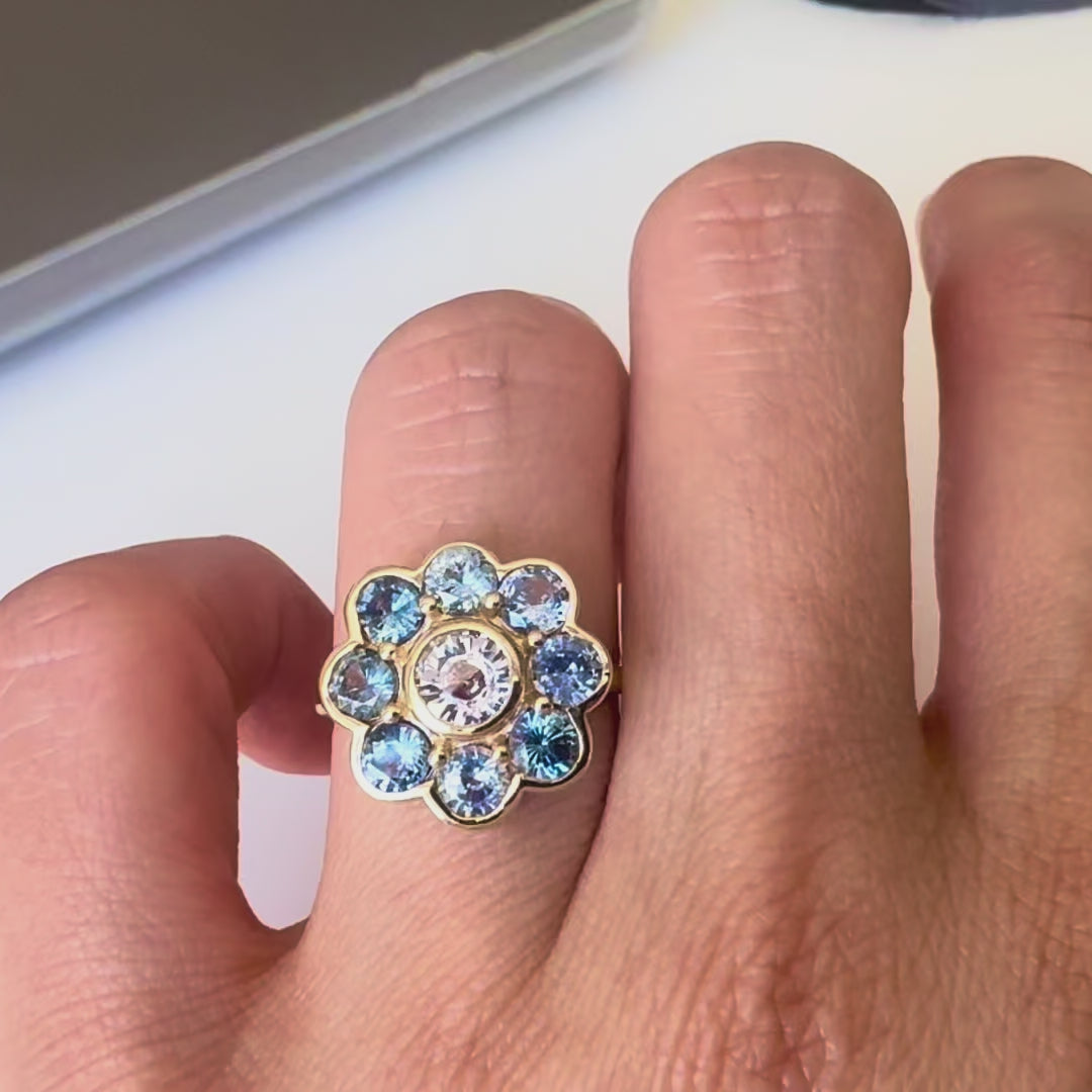 Gold ring with blue sapphires on a hand against white background
