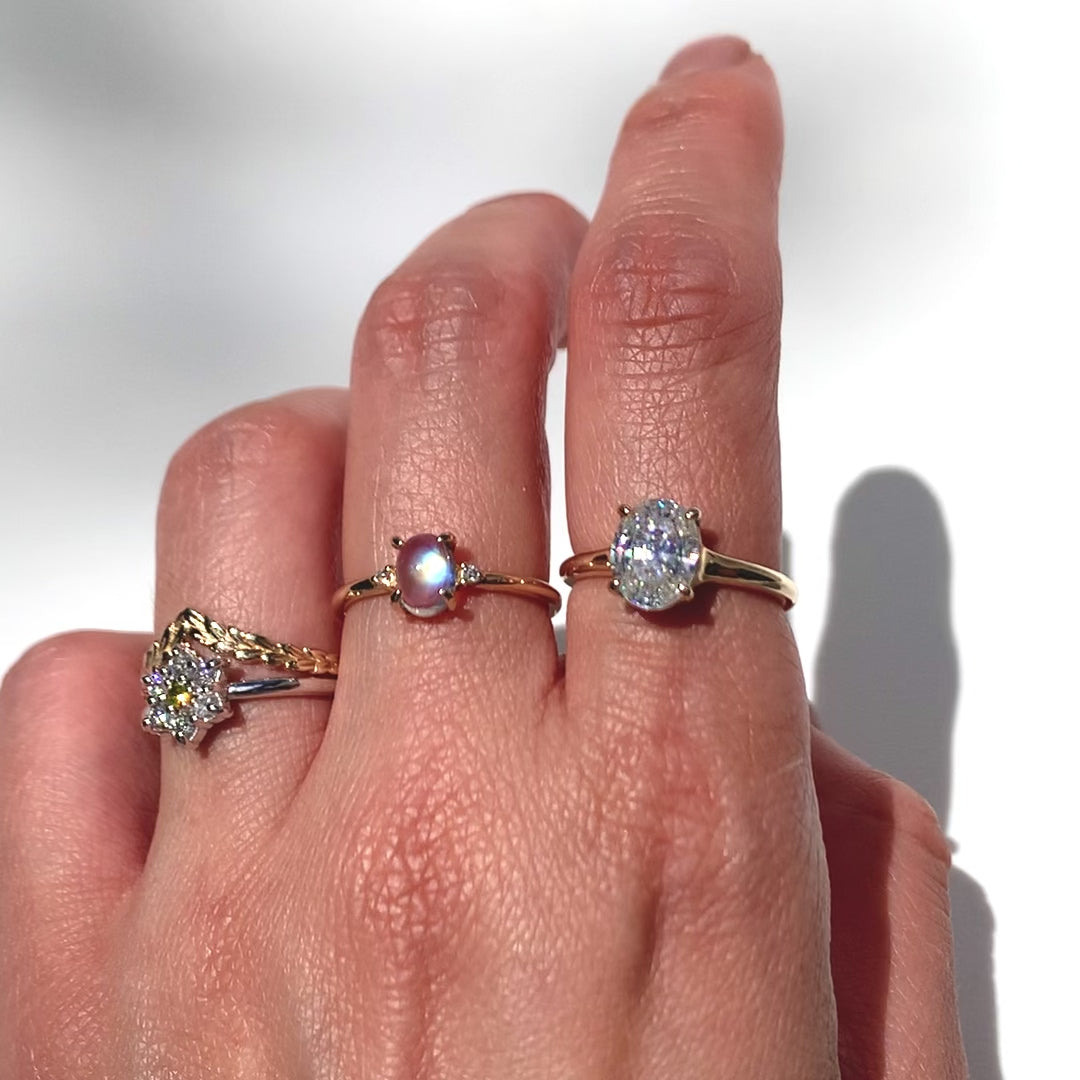 Oval step cut 2ct diamond ring with other gemstone rings  on a hand against white background 