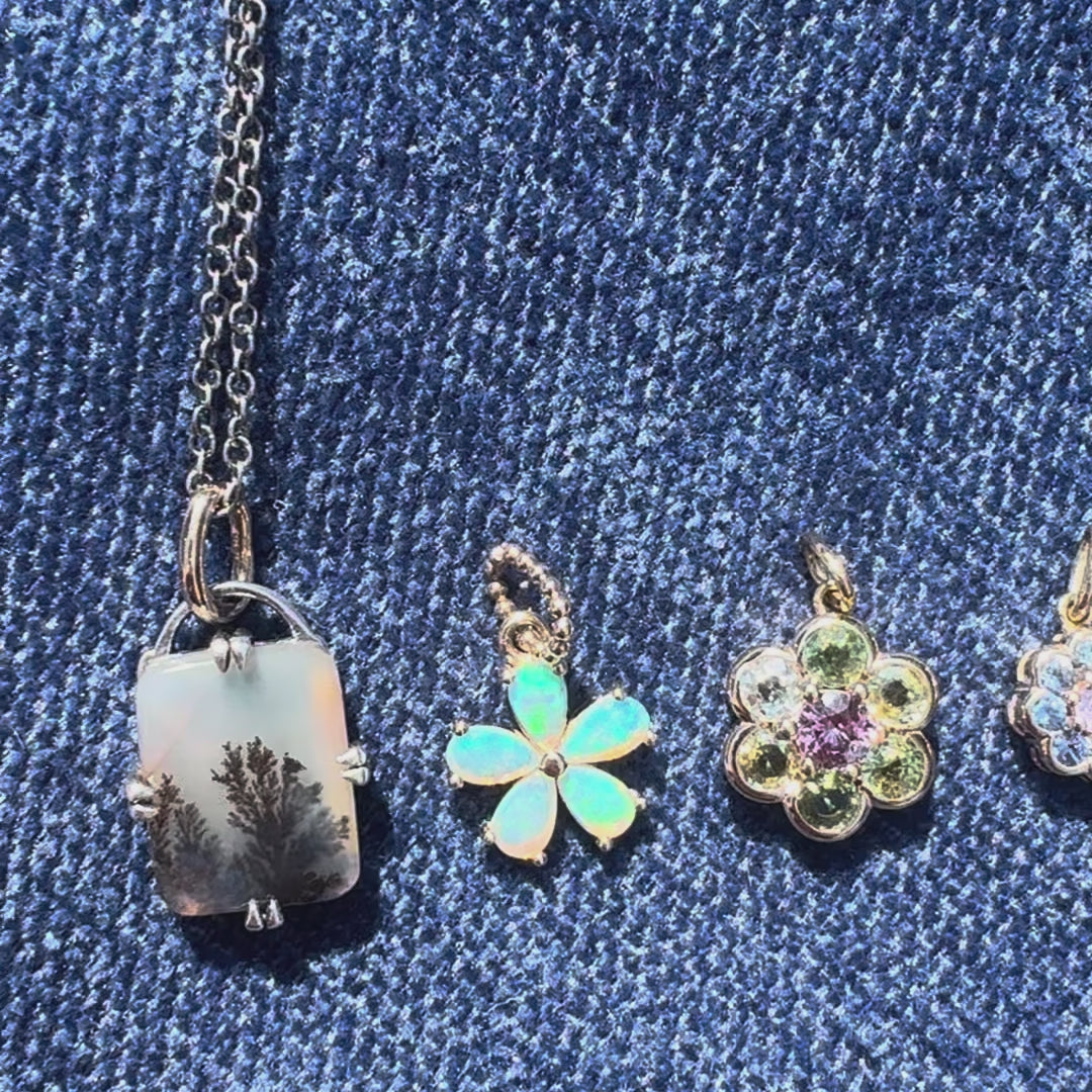 five gemstone charms on a blue background