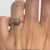 Gold rings with a round diamond stacked on a finger against a white background
