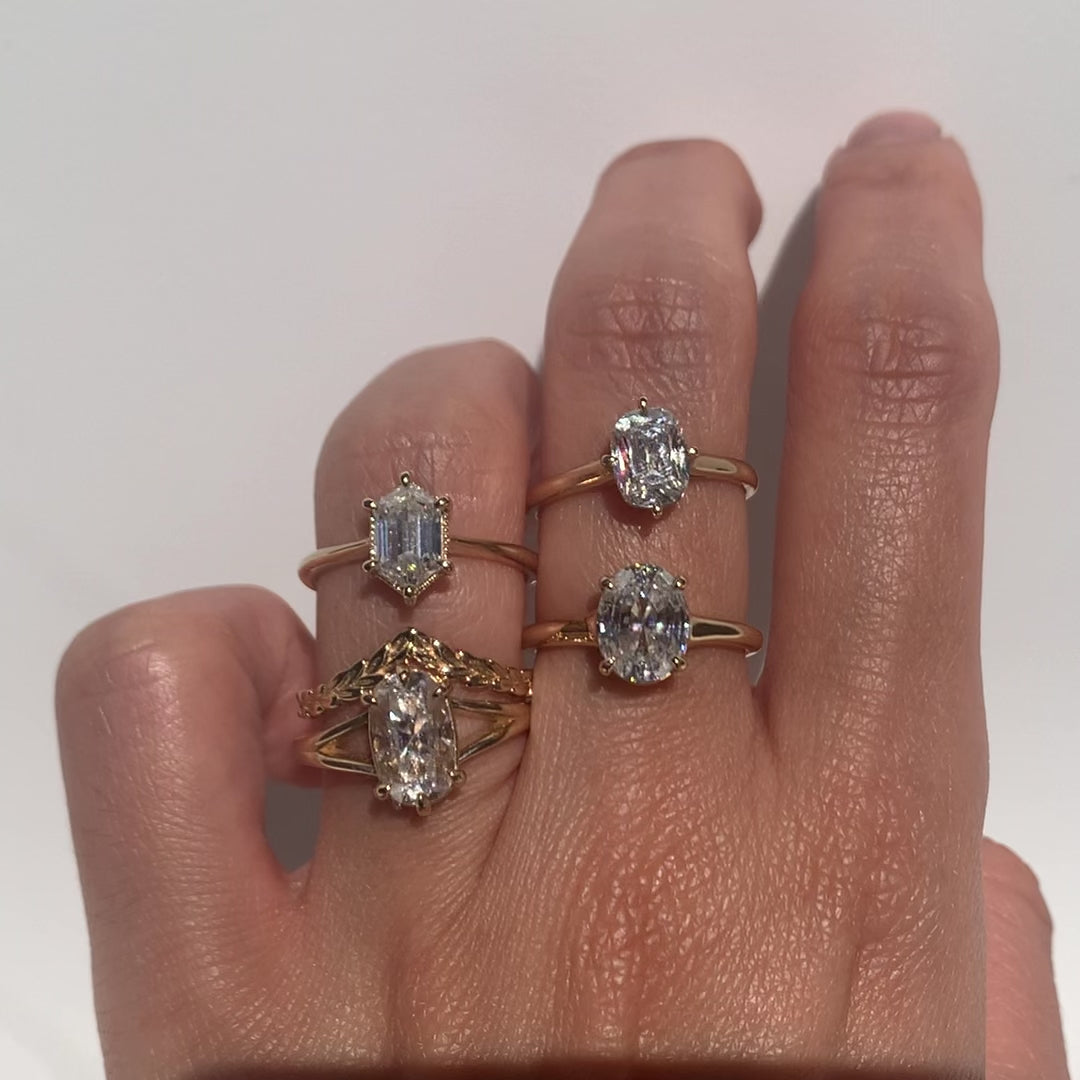 Oval step cut 2ct diamond ring with other gemstone rings  on a hand against white background 