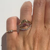 Gold rings  with pink and white gemstones  on a finger against a white background