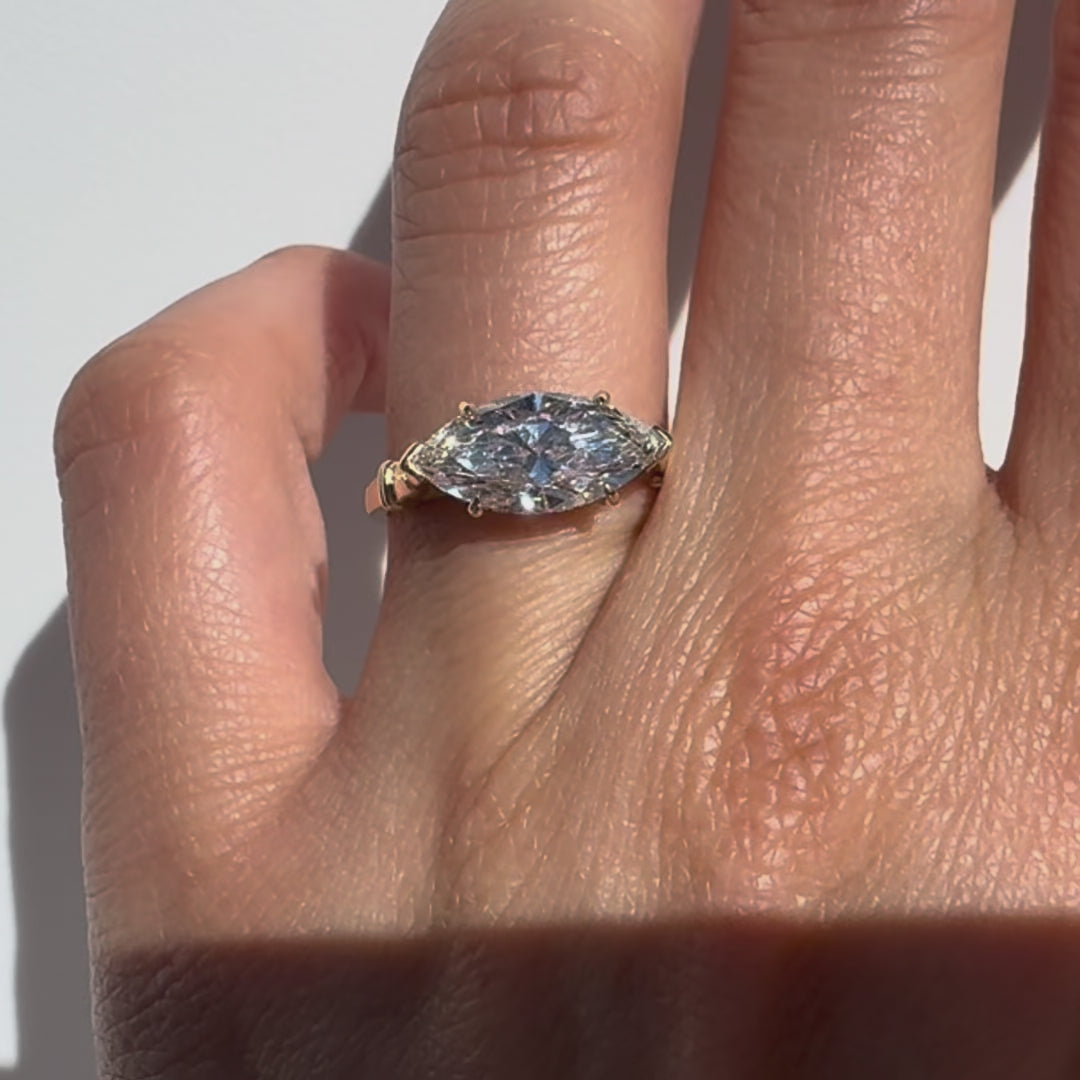 Gold ring with a large marquise shaped diamond on a white background