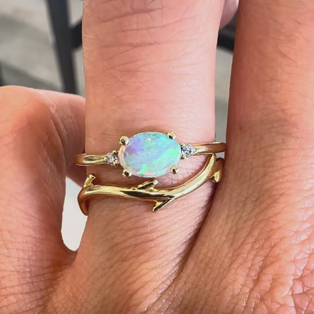 Two gemstone rings on a hand against a neutral background. 