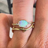 Two gemstone rings on a hand against a neutral background. 