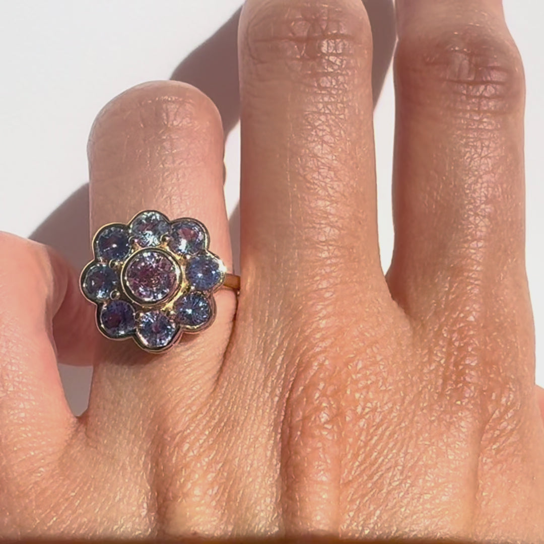 Gold ring with blue sapphires on a hand against white background
