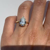 A pear cut diamond ring on a hand against white background.