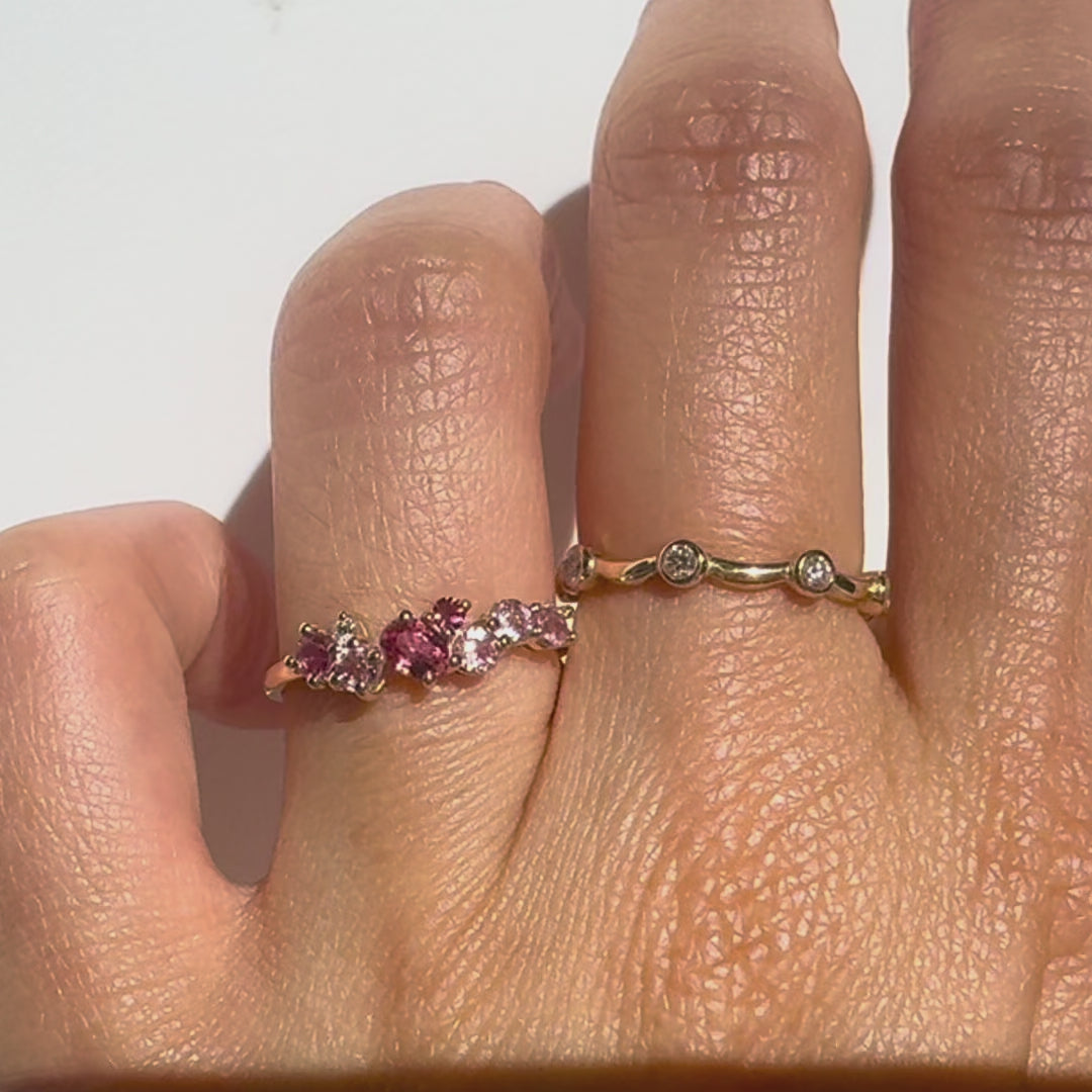 Gold rings  with pink and white gemstones  on a finger against a white background